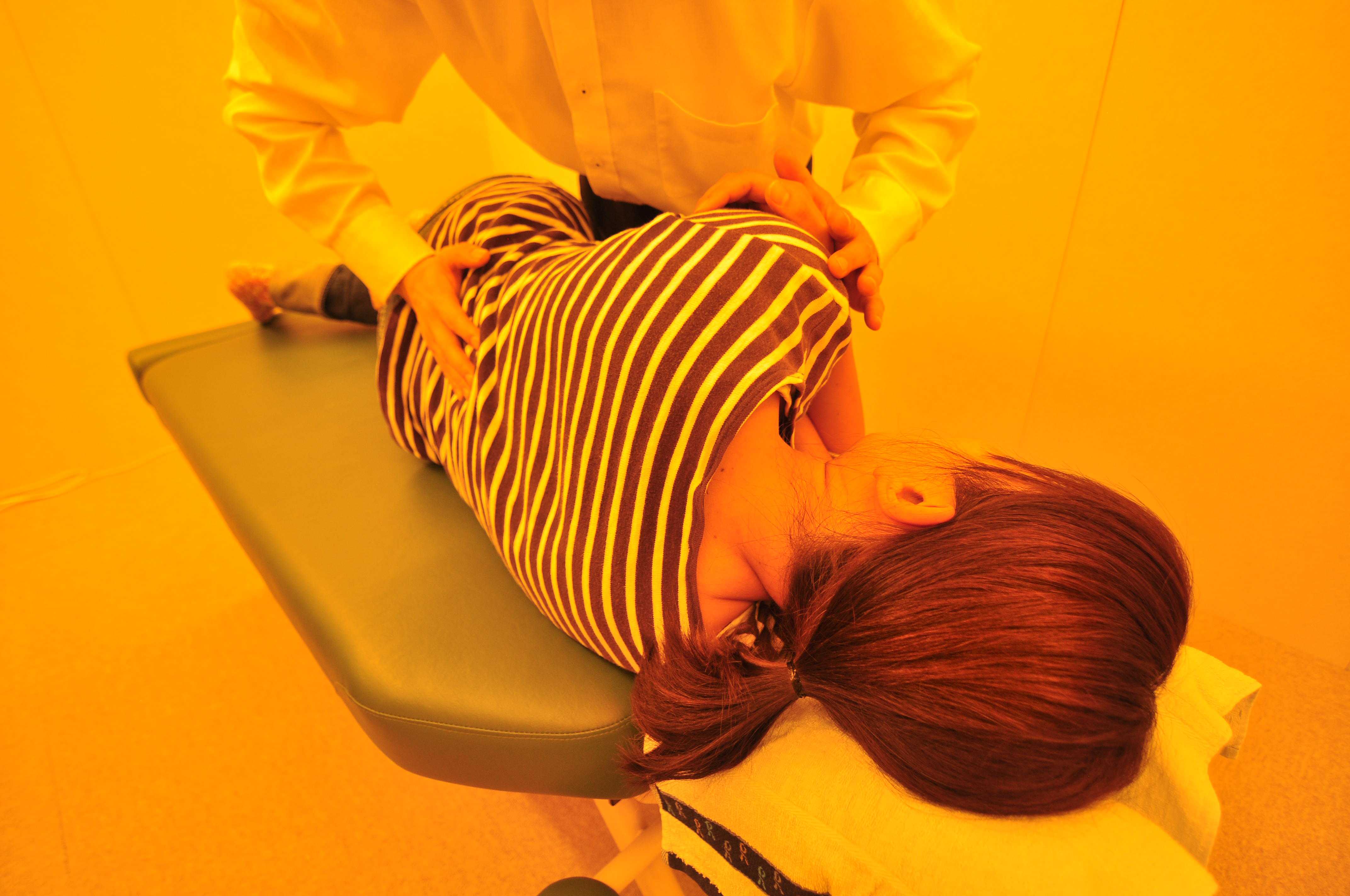 整体のオリア施術室にて横向きで腰の施術を受ける女性の写真1